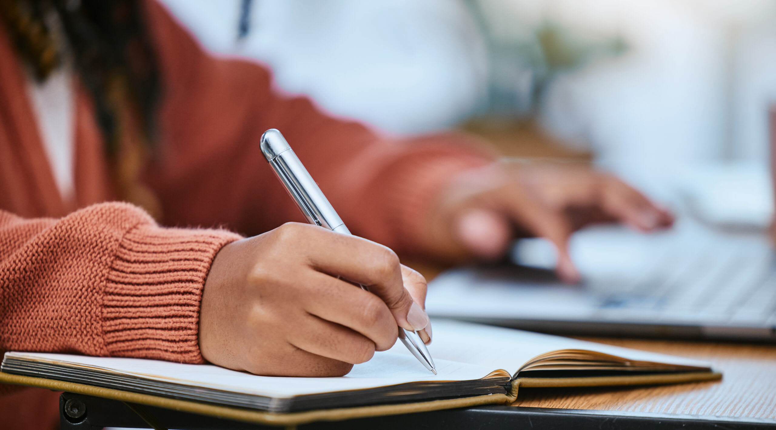 Student, writing and hand with notebook for studying, learning and creative notes for academic class. University, college and zoom of hands with pen to write schedule information, planning and ideas.