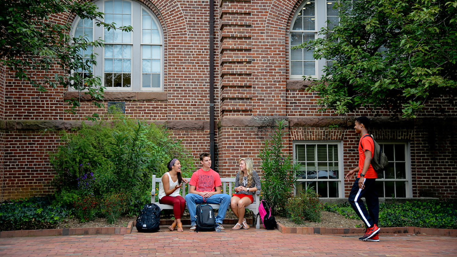 Students chat in front of Holladay Hall on campus.