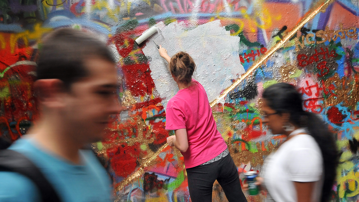 Walkers pass by a student as she whitewashes the Free Expression Tunnel in preparation for Respect The Pack.