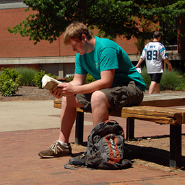 Student reads between classes on a sunny Spring day on main campus. 