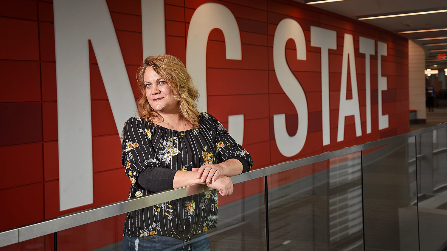 Student Alison Plumley stands in front of the words "NC State" at Talley Student Union.