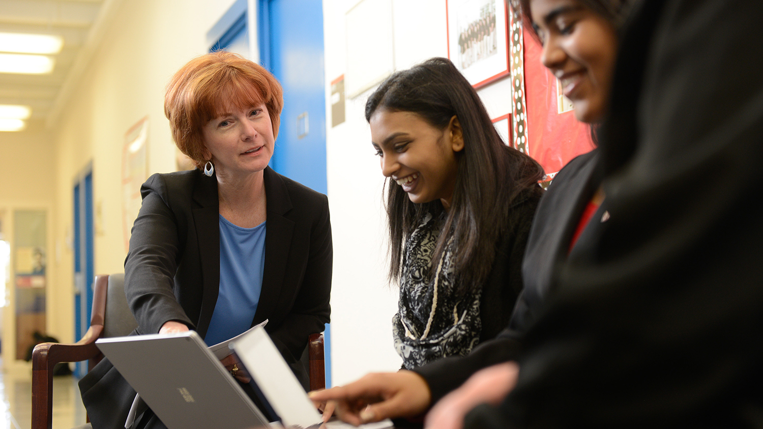 A faculty member talks with two students.