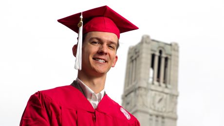 Logan Skeehan in a graduation gown with the Bell Tower in the background. 