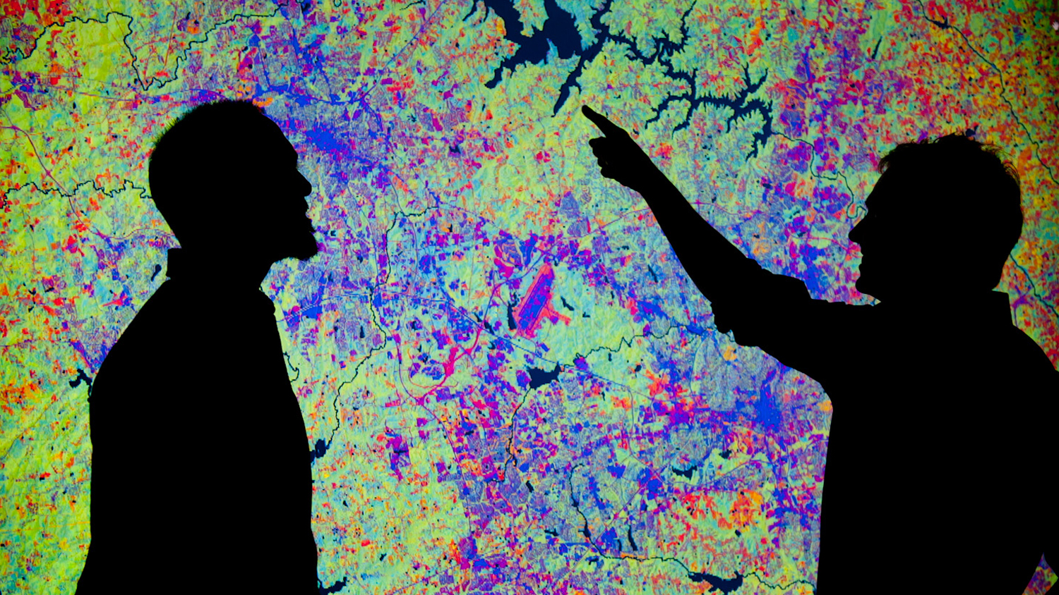 Two human shadows against a brightly colored map.