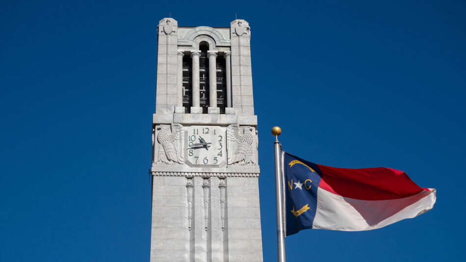 The state flag flies in front of the NC State Memorial Belltower on a fall morning. Photo by Becky Kirkland.