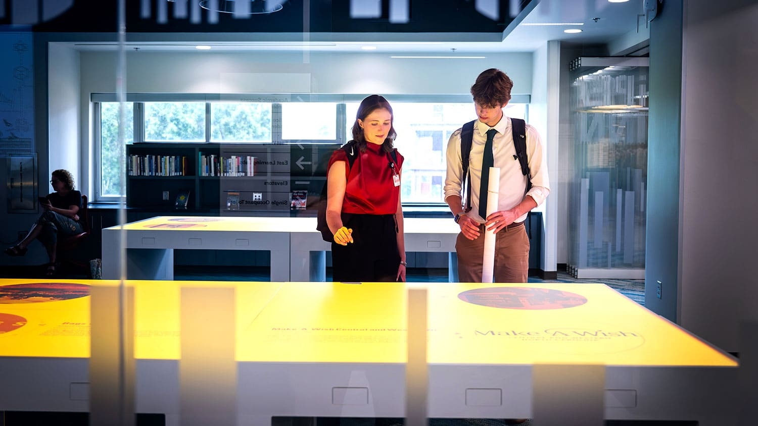 Two people stand looking down at a table featuring a digital visualization.