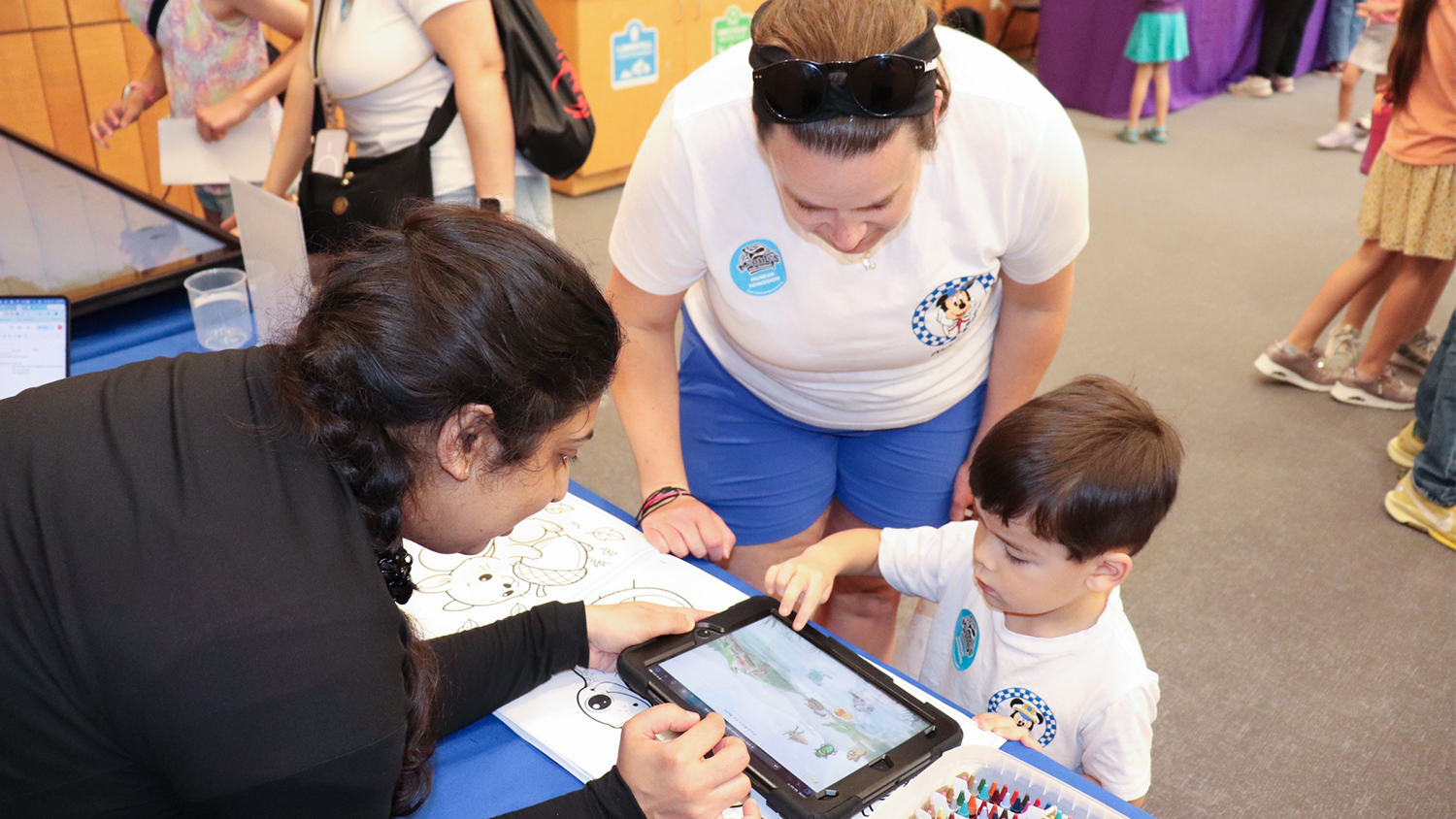 A professor helps a young boy navigate a screen to help him learn about food webs and ecosystems